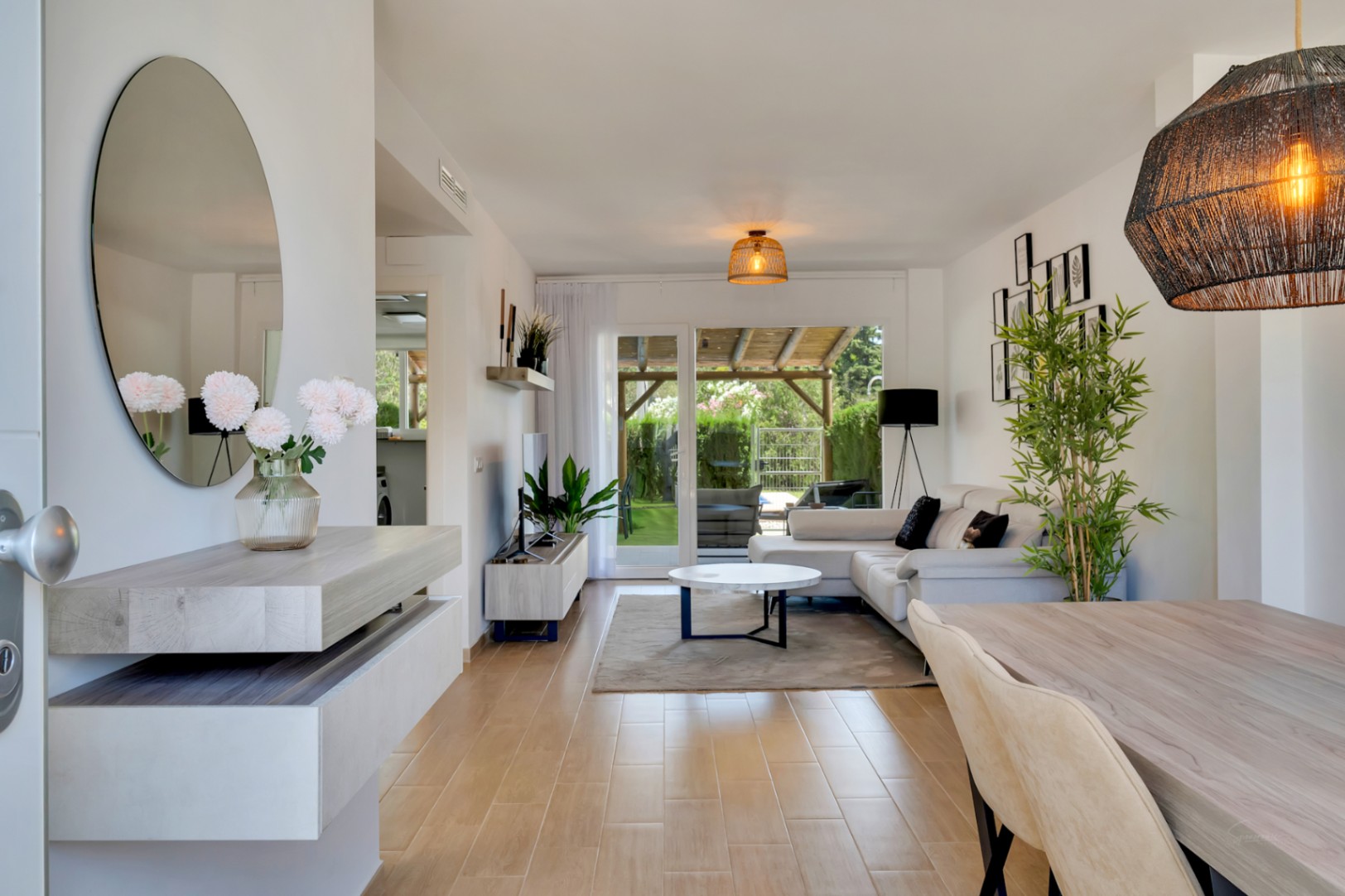 Salon-salle à manger à aire ouverte avec sol en grès cérame effet bois, mobilier moderne et accès direct au patio privé par de grandes baies vitrées.