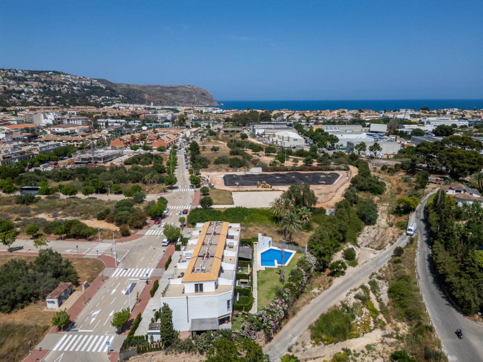 Vue aérienne du complexe résidentiel moderne avec piscine commune, illustrant son emplacement privilégié à Jávea entre centre-ville et mer Méditerranée.