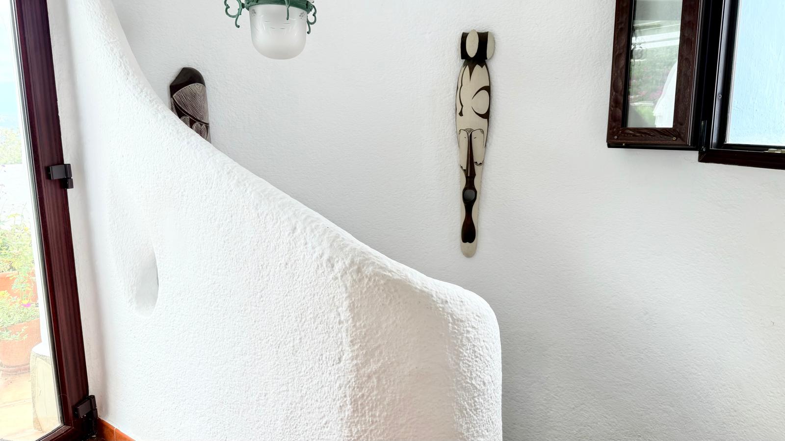 Détail de l'escalier intérieur incurvé avec des murs en plâtre blanc texturé, illustrant le style architectural organique d'Ibiza.