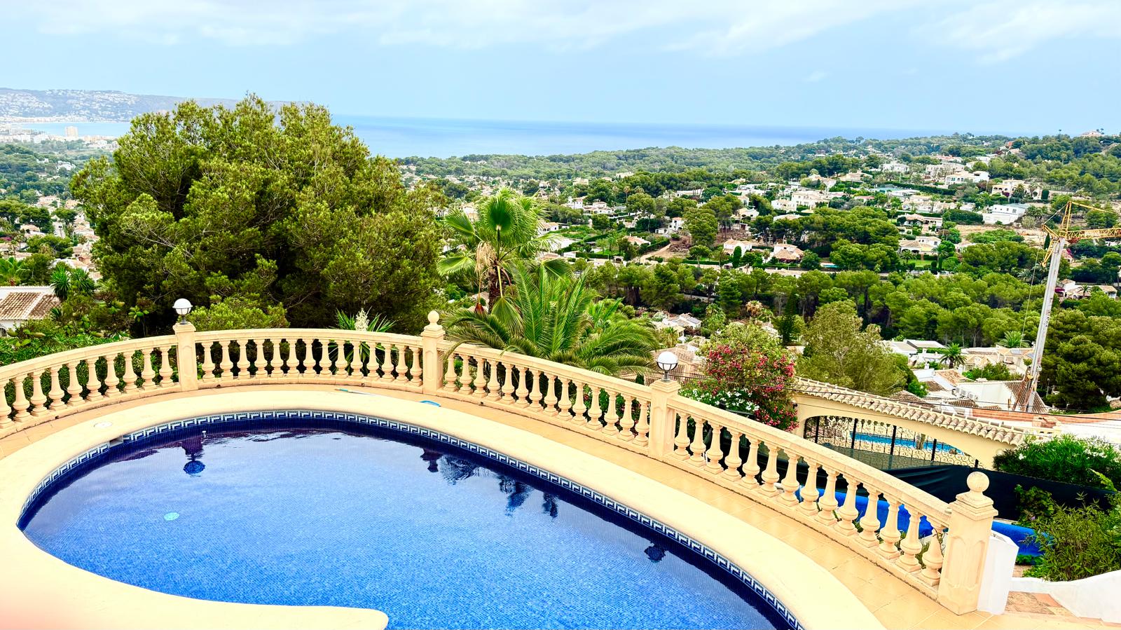 Piscine privée avec mosaïque bleue et balustrade classique, offrant une vue panoramique sur la mer Méditerranée et la végétation luxuriante de Jávea.