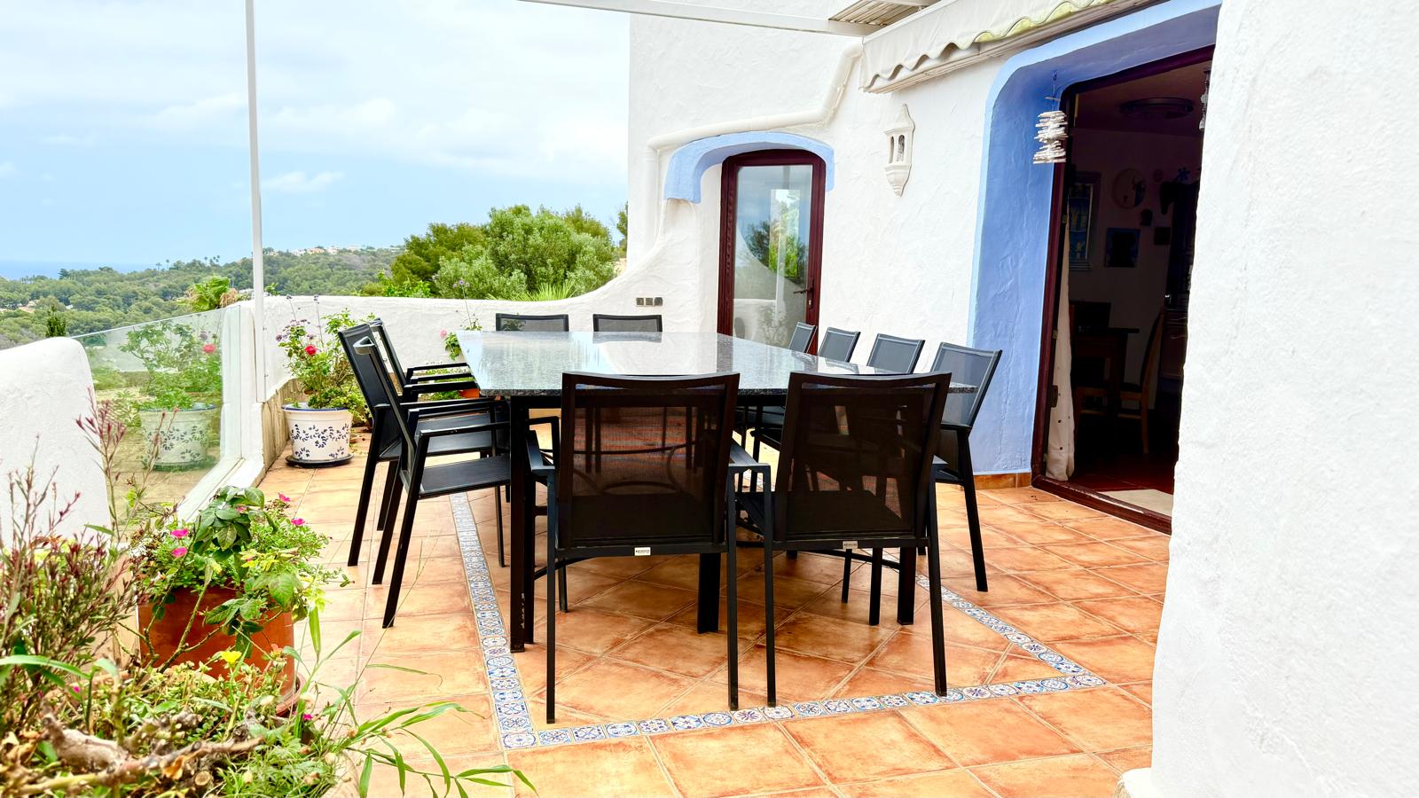 Terrasse de salle à manger extérieure avec table en granit, carrelage en terre cuite et vue dégagée sur le paysage côtier de Jávea.