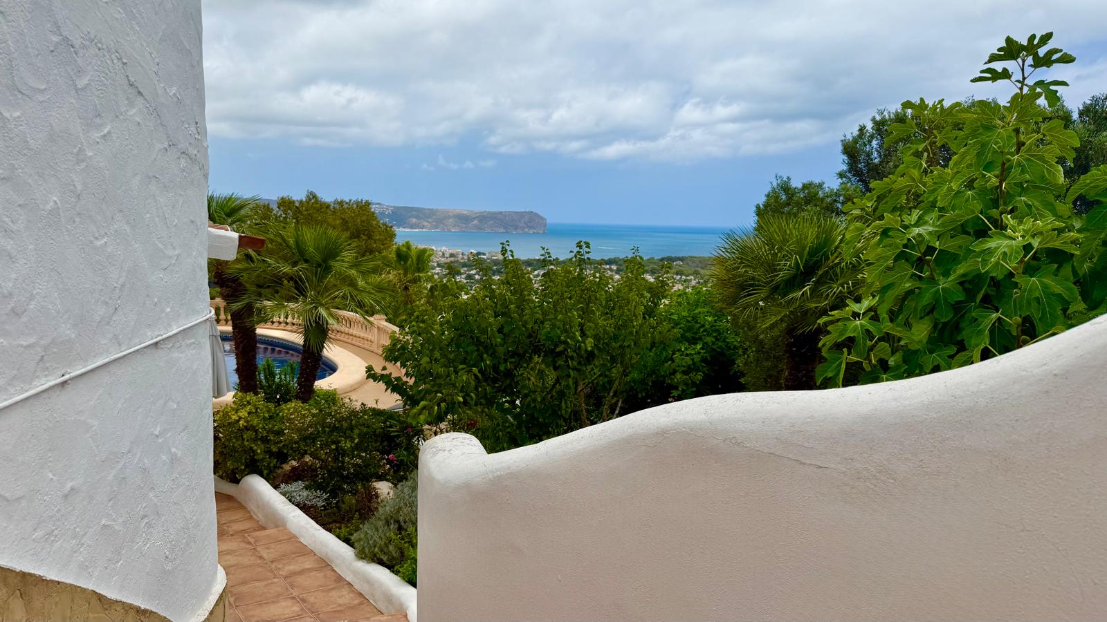 Vue panoramique sur la mer et la côte de Jávea depuis les escaliers extérieurs, bordés de murs blancs incurvés et d'une végétation méditerranéenne.