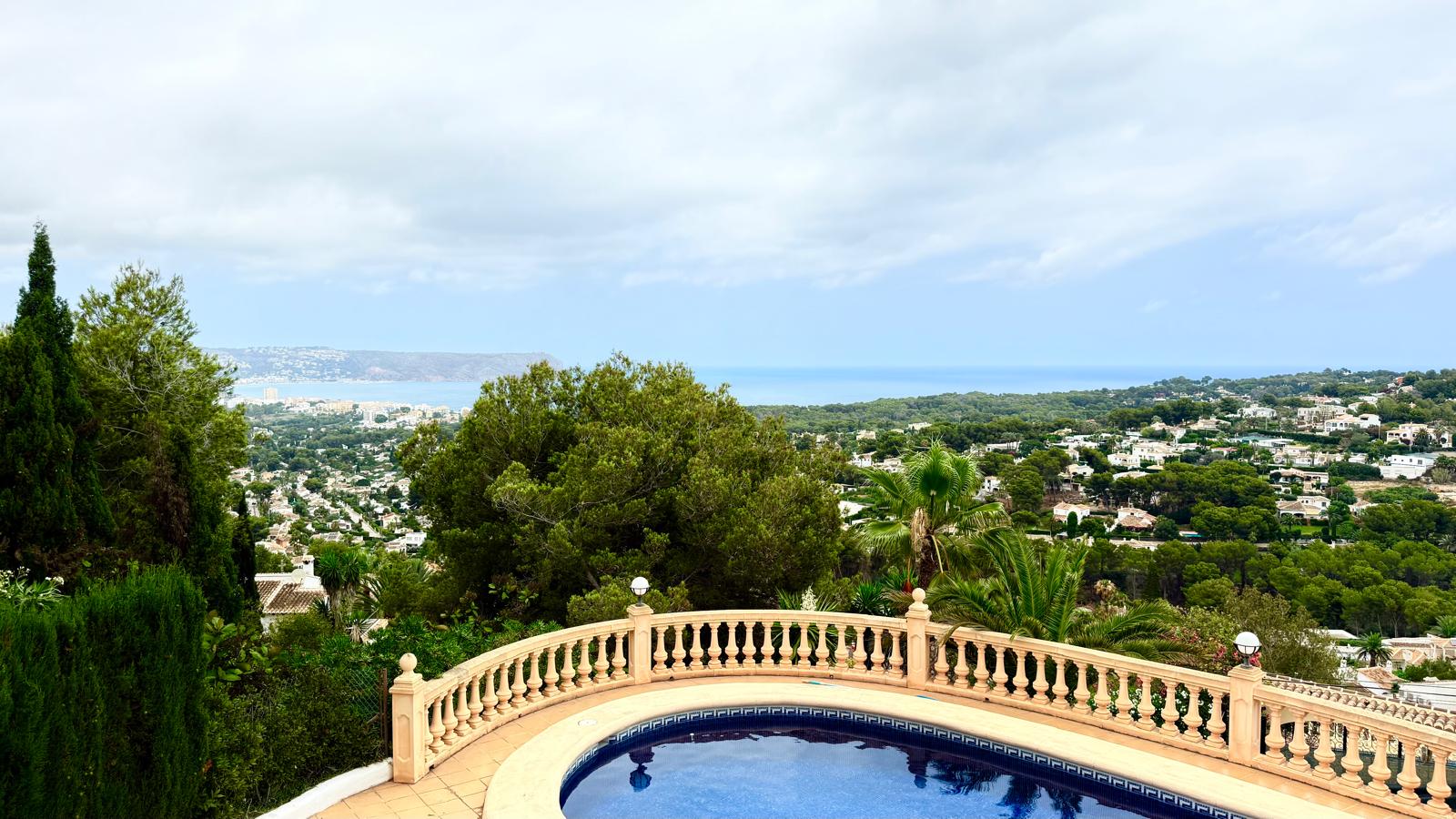 Vue panoramique sur la mer Méditerranée et la baie de Jávea depuis la terrasse supérieure, avec sa balustrade en pierre classique surplombant la piscine.