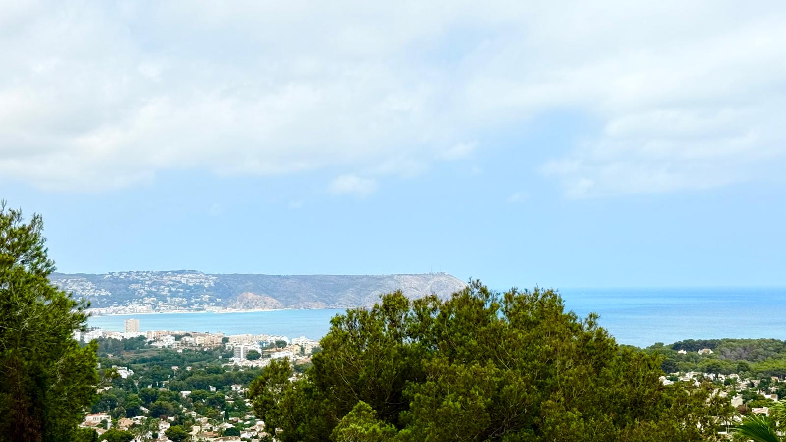 Vues panoramiques sur la baie de Jávea et la mer Méditerranée, avec le Cap de Sant Antoni à l'horizon, encadrées par les pins matures de la propriété.