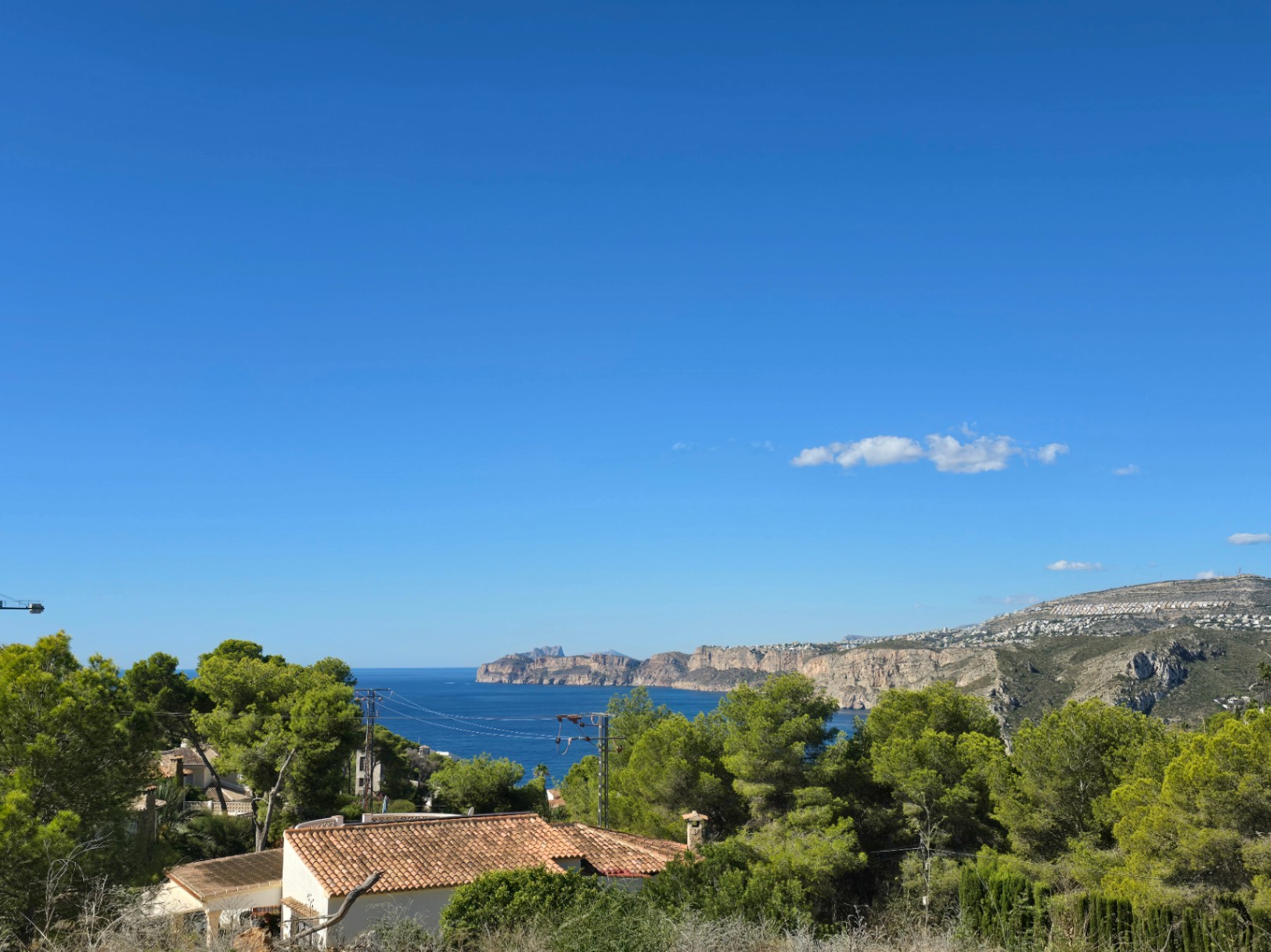Vues panoramiques sur la mer Méditerranée et les falaises de Jávea depuis le terrain surélevé, entouré de pins et de végétation locale.