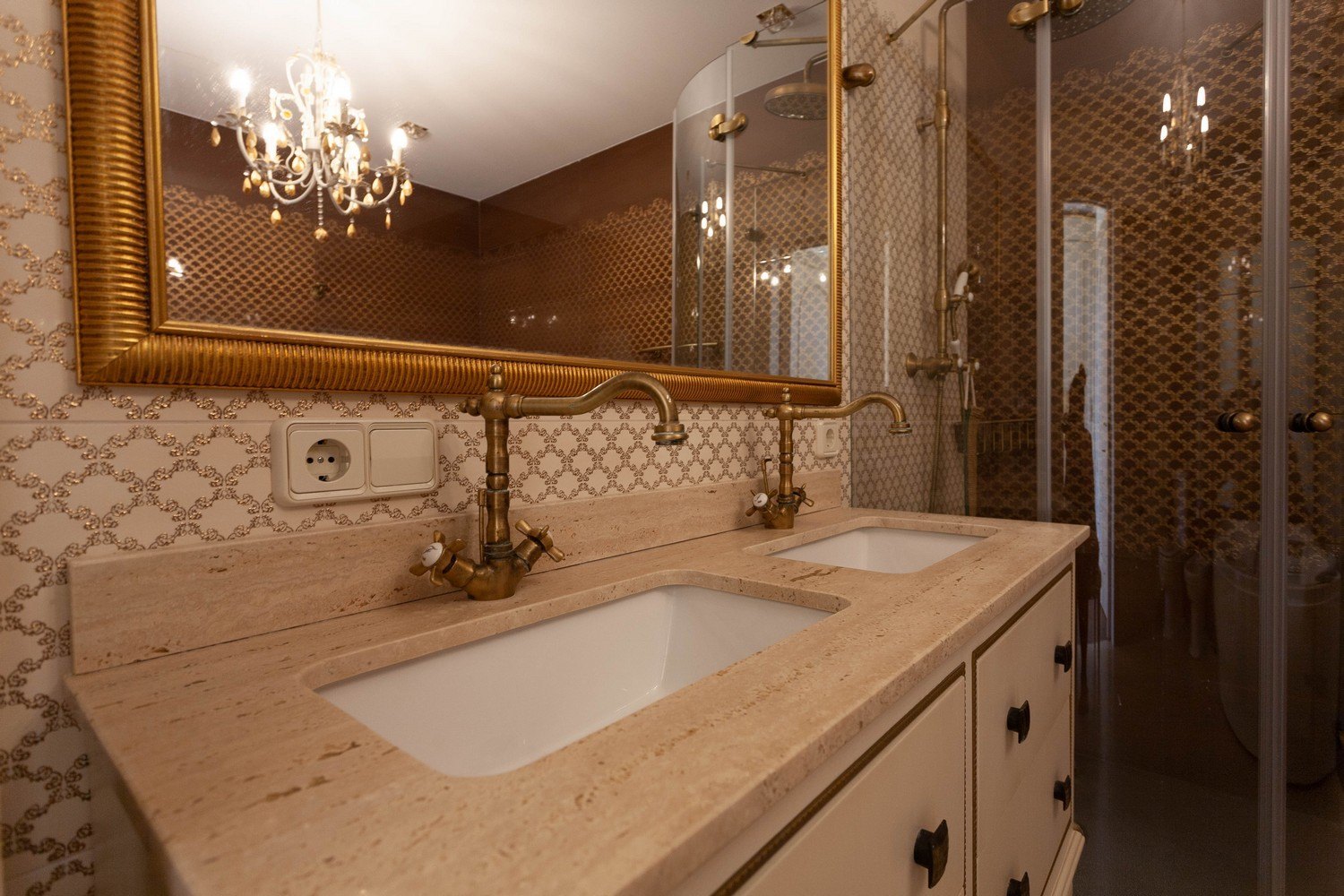 Détail de la salle de bain avec double vasque en marbre et robinetterie en laiton.
