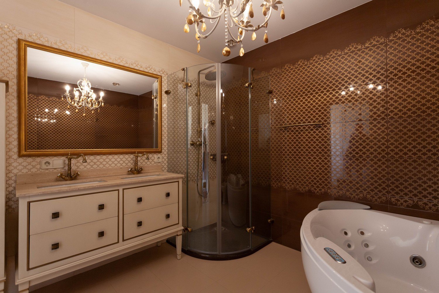 Détail de salle de bain avec meuble-lavabo double, douche d'angle et baignoire jacuzzi. Lustre élégant.