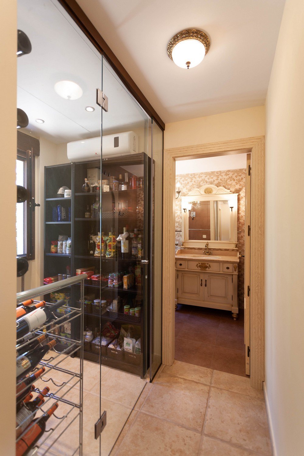 Détail du cellier avec porte en verre et salle de bain avec meuble-lavabo classique.