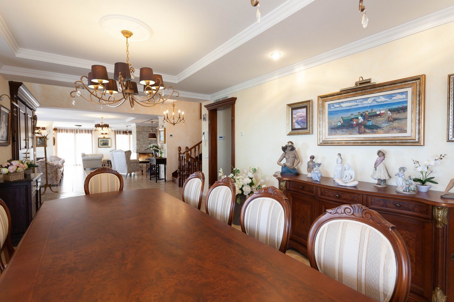Salle à manger avec table en bois foncé, chaises rembourrées et buffet classique avec sculptures décoratives.
