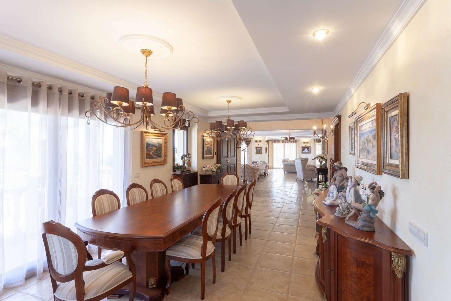 Salle à manger élégante avec table en bois foncé, chaises rembourrées et lustres classiques.
