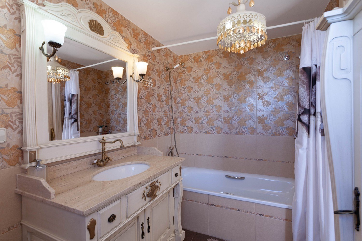 Salle de bain classique avec lavabo en marbre, miroir orné et baignoire avec douche.