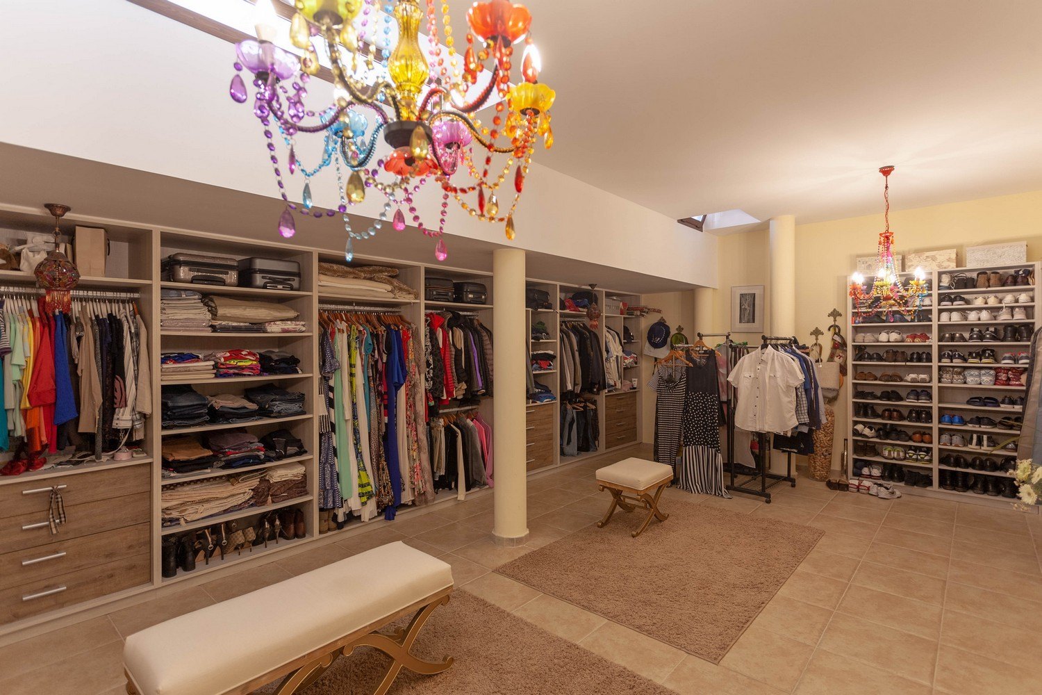 Vaste dressing avec placards intégrés, bancs rembourrés et lustre multicolore.