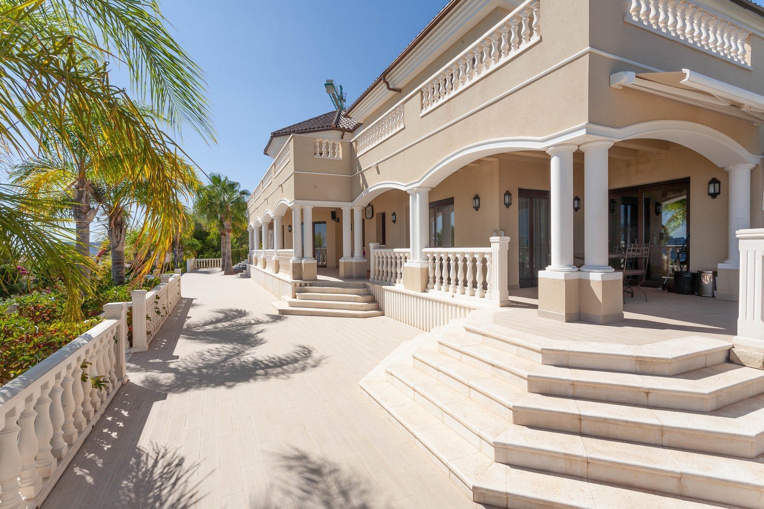 Vue extérieure de la villa avec terrasse en pierre et balustrade classique.