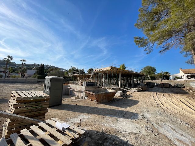 Construction de villa à Moraira : structure en béton avec supports métalliques sous ciel bleu.