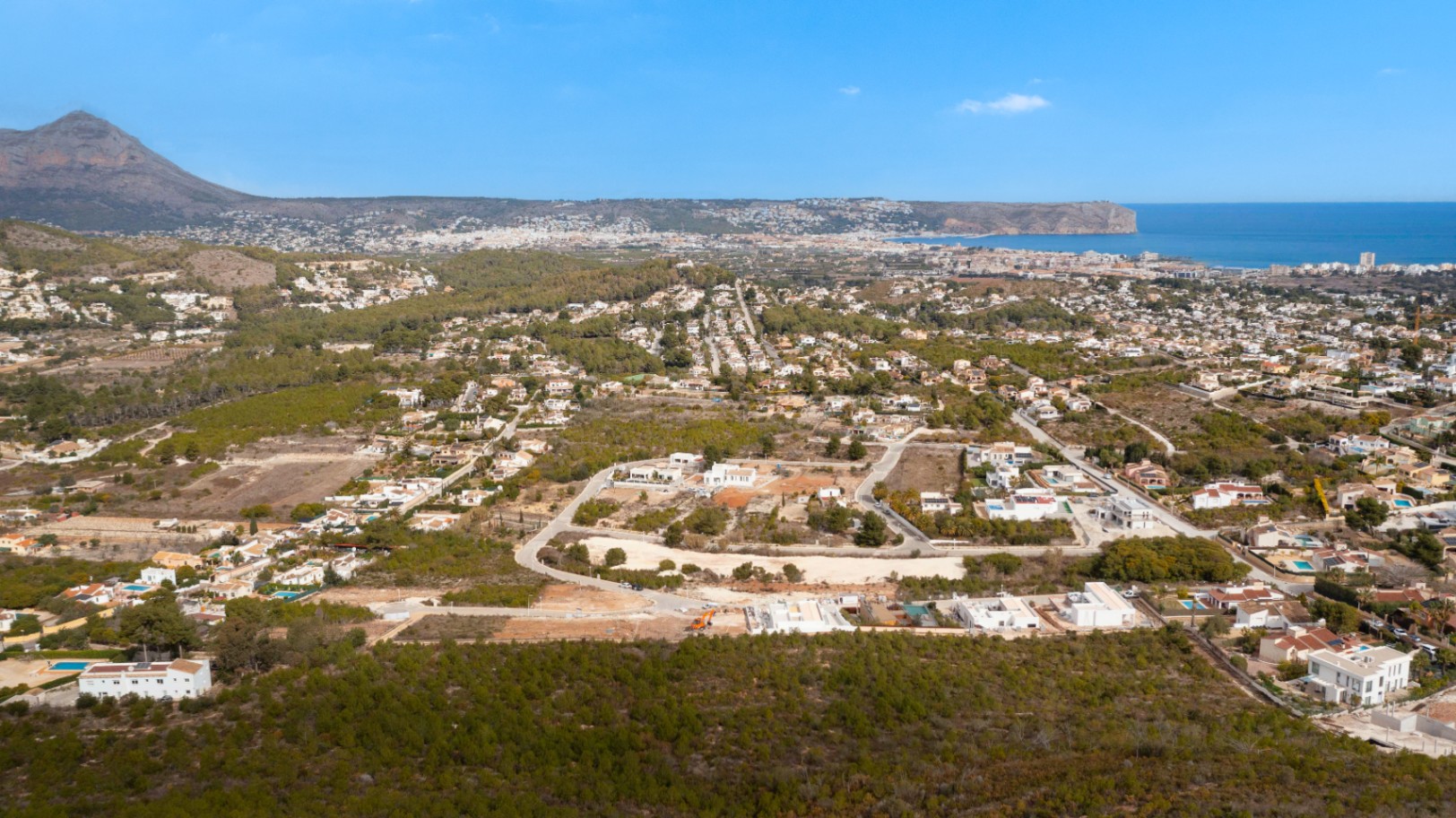Vue aérienne panoramique de Lomas Del Rey à Jávea, illustrant la proximité du Montgó et de la mer Méditerranée parmi les parcelles résidentielles.