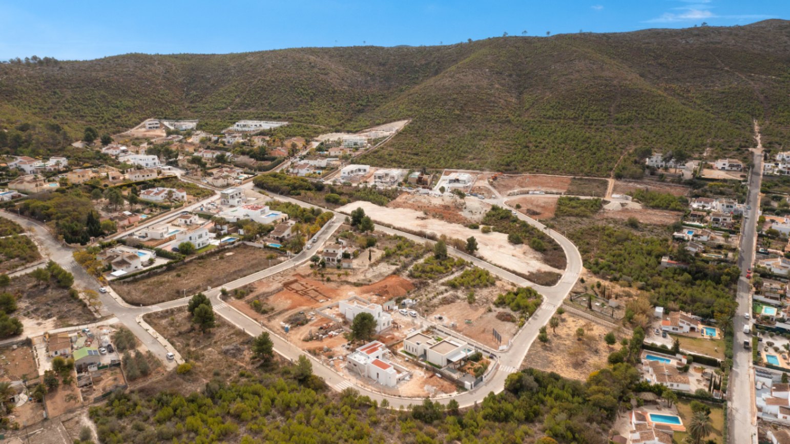 Vue aérienne de la villa en construction à Jávea, mettant en valeur son cadre naturel et d'autres résidences.