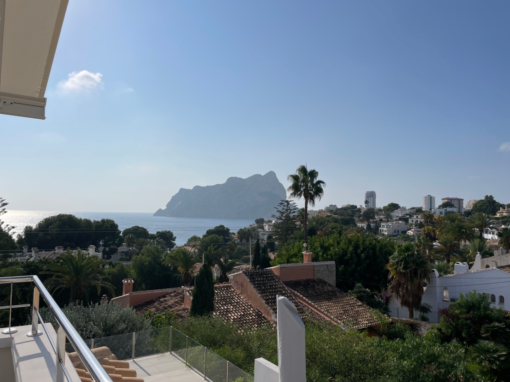 Vue panoramique depuis une terrasse avec garde-corps en inox et verre, donnant sur le Peñón de Ifach et le littoral méditerranéen.