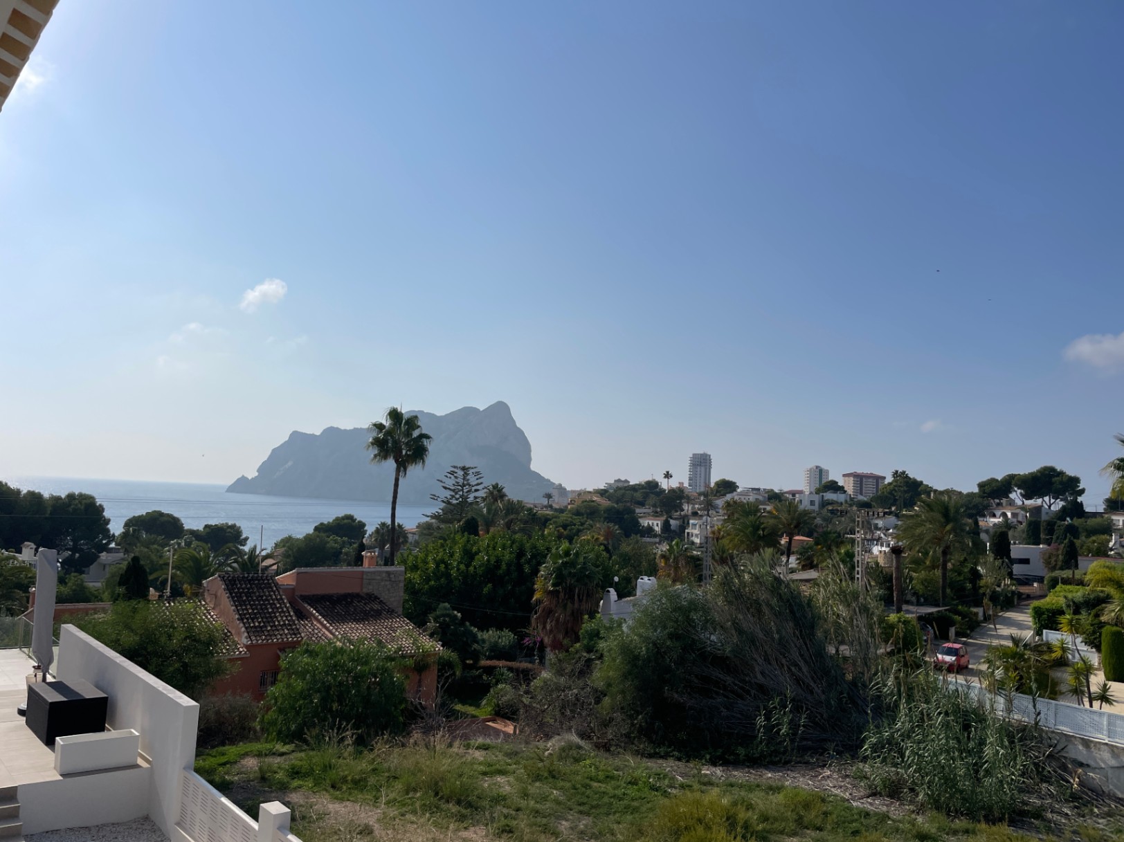Vue panoramique sur le Peñon de Ifach et la mer Méditerranée depuis le terrain surélevé à Bassetes, Calpe, entouré de végétation locale et de villas.