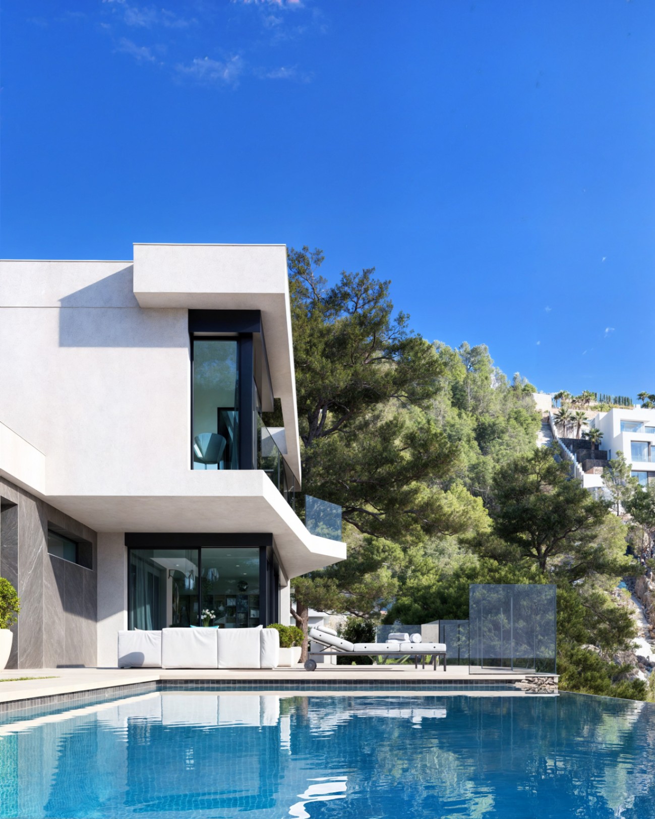 Façade moderne avec porte-à-faux blancs, piscine à débordement et terrasse avec mobilier design intégrée dans une pinède méditerranéenne.