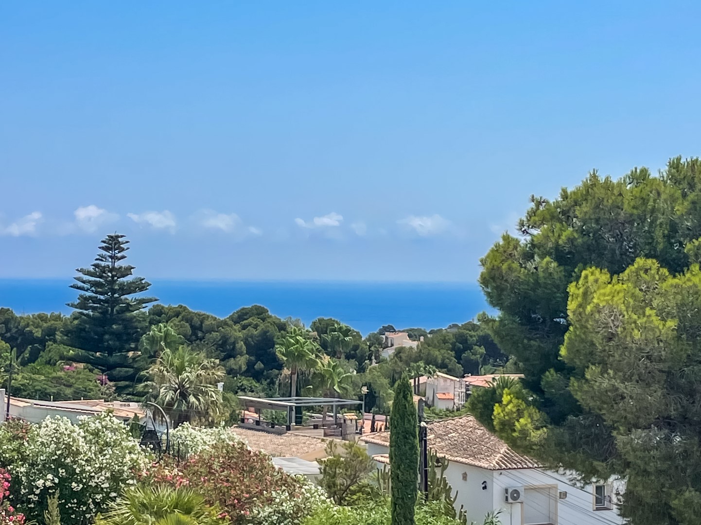 Vue panoramique sur la mer Méditerranée depuis la villa, entourée d'une végétation luxuriante et des toits traditionnels du quartier résidentiel de Balcón al Mar.