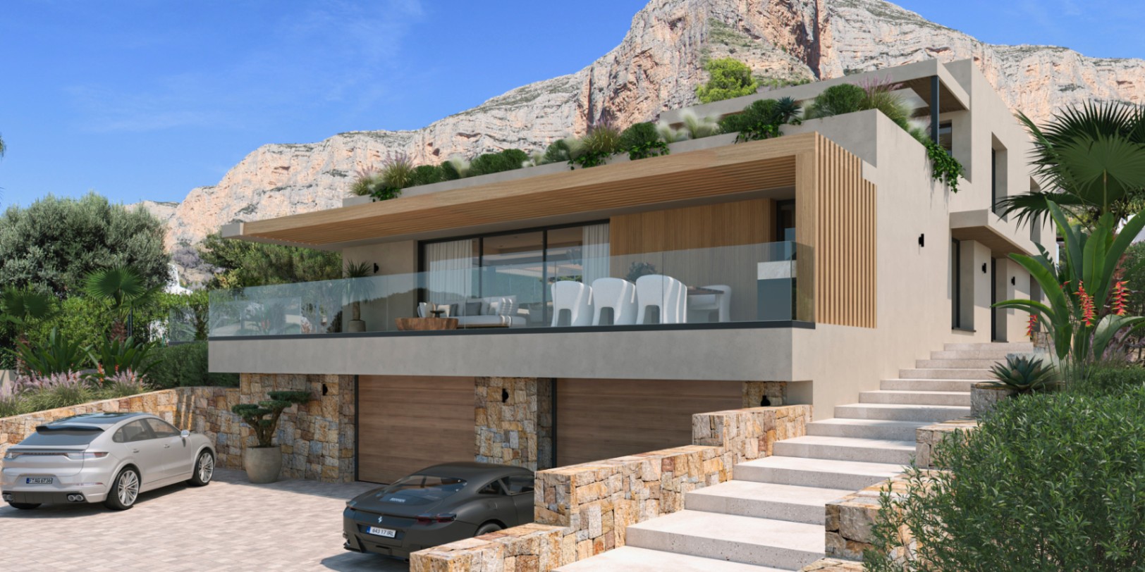 Façade moderne avec murs en pierre naturelle, double garage et grande terrasse avec garde-corps en verre au pied du massif du Montgó.