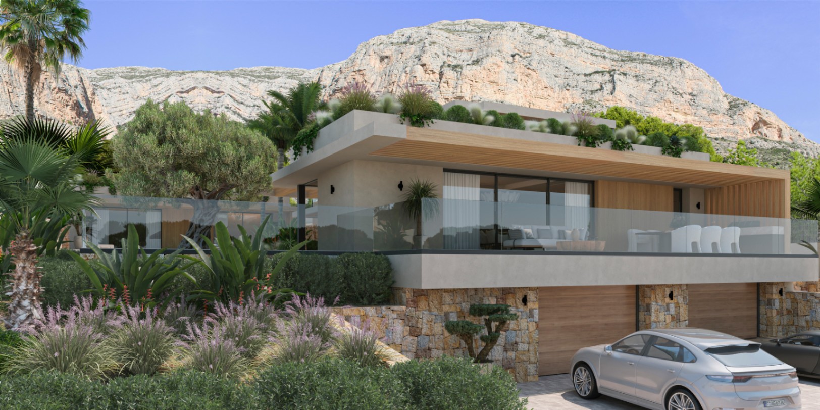 Façade moderne avec murs en pierre naturelle, grandes baies vitrées et terrasses en verre, située au pied de l'imposant massif du Montgó à Jávea.