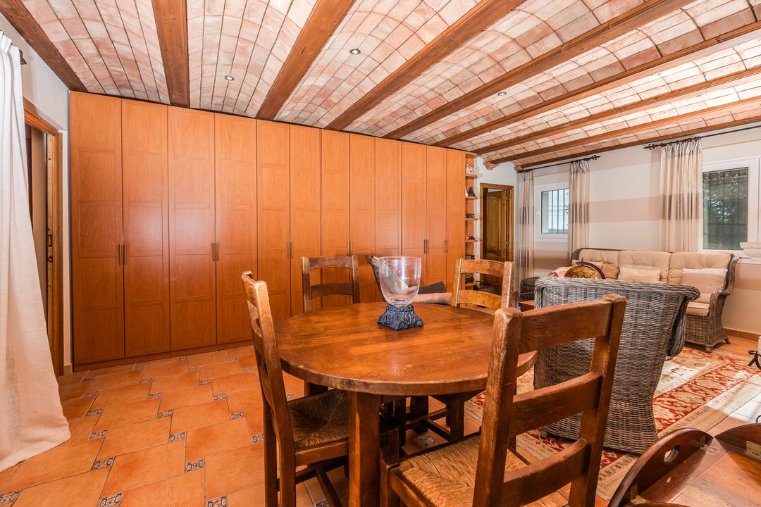 Séjour avec plafond en voûte catalane et poutres apparentes, sol en terre cuite et un grand placard intégré en bois sur mesure.