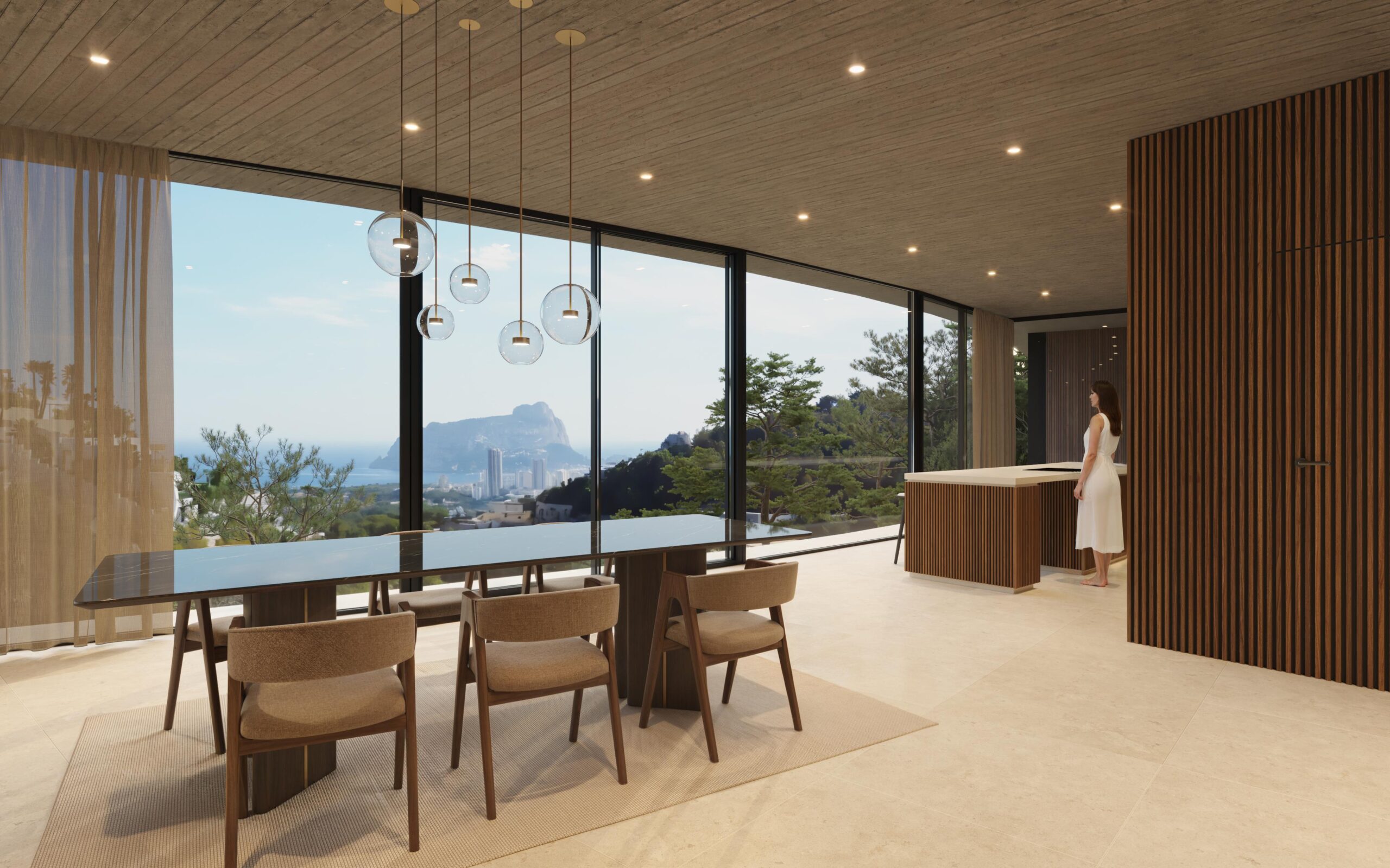 Salle à manger ouverte avec table en marbre noir, suspensions sphériques et baies vitrées offrant une vue sur le Peñón de Ifach et le littoral méditerranéen.
