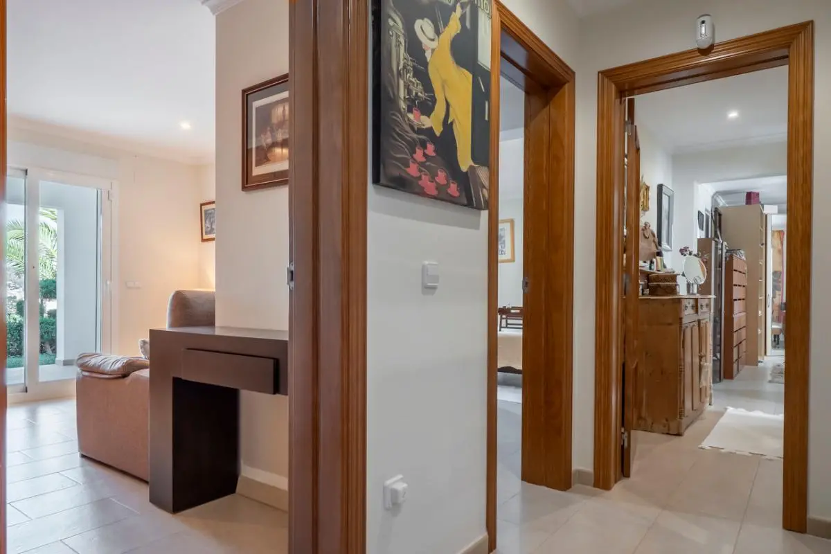 Couloir avec encadrements de portes en bois, carrelage clair et vues sur le salon et les pièces adjacentes dotées d'un mobilier classique.
