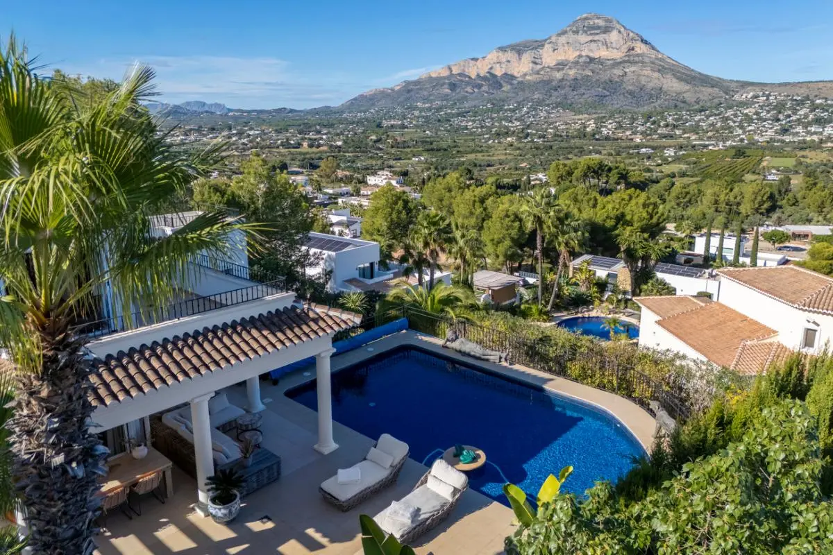 Vue surélevée de la piscine privée et de la terrasse couverte à colonnes, offrant un panorama dégagé sur la vallée et le massif du Montgó.