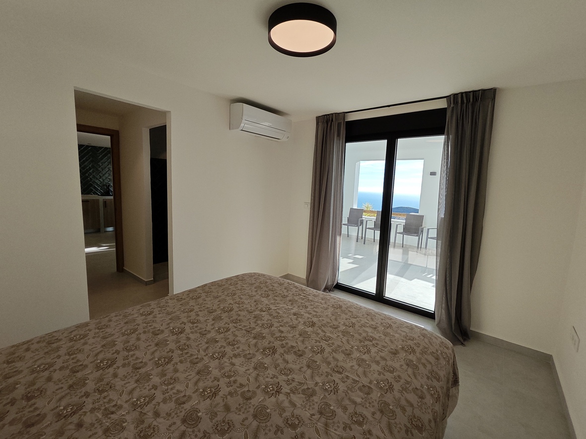 Chambre avec accès direct à une terrasse offrant une vue sur la mer. Équipée de la climatisation, d'un décor neutre et de grandes baies vitrées coulissantes.