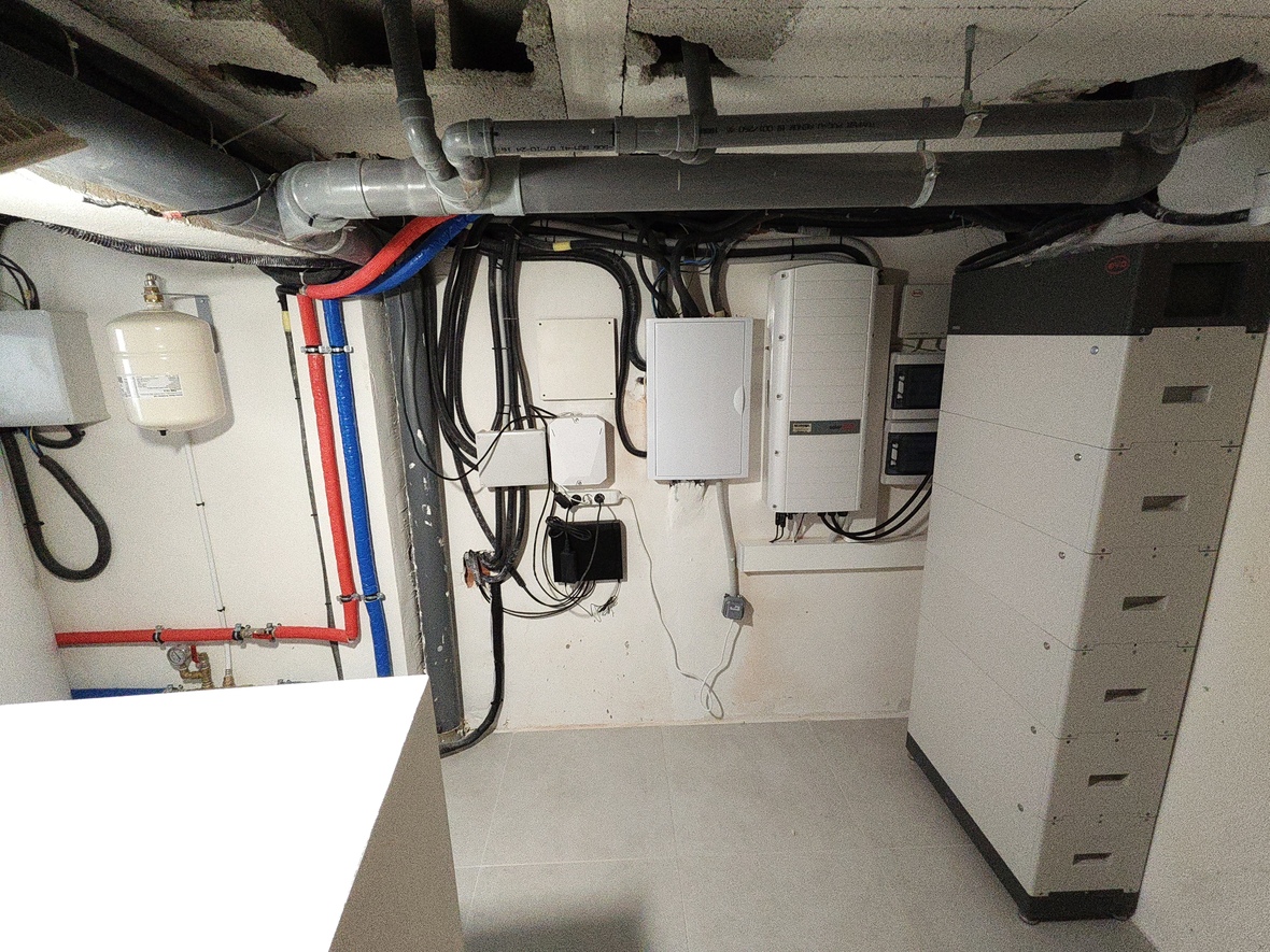 Local technique comprenant un onduleur SolarEdge, une batterie de stockage BYD et une installation de plomberie avec vase d'expansion et tuyaux PEX.