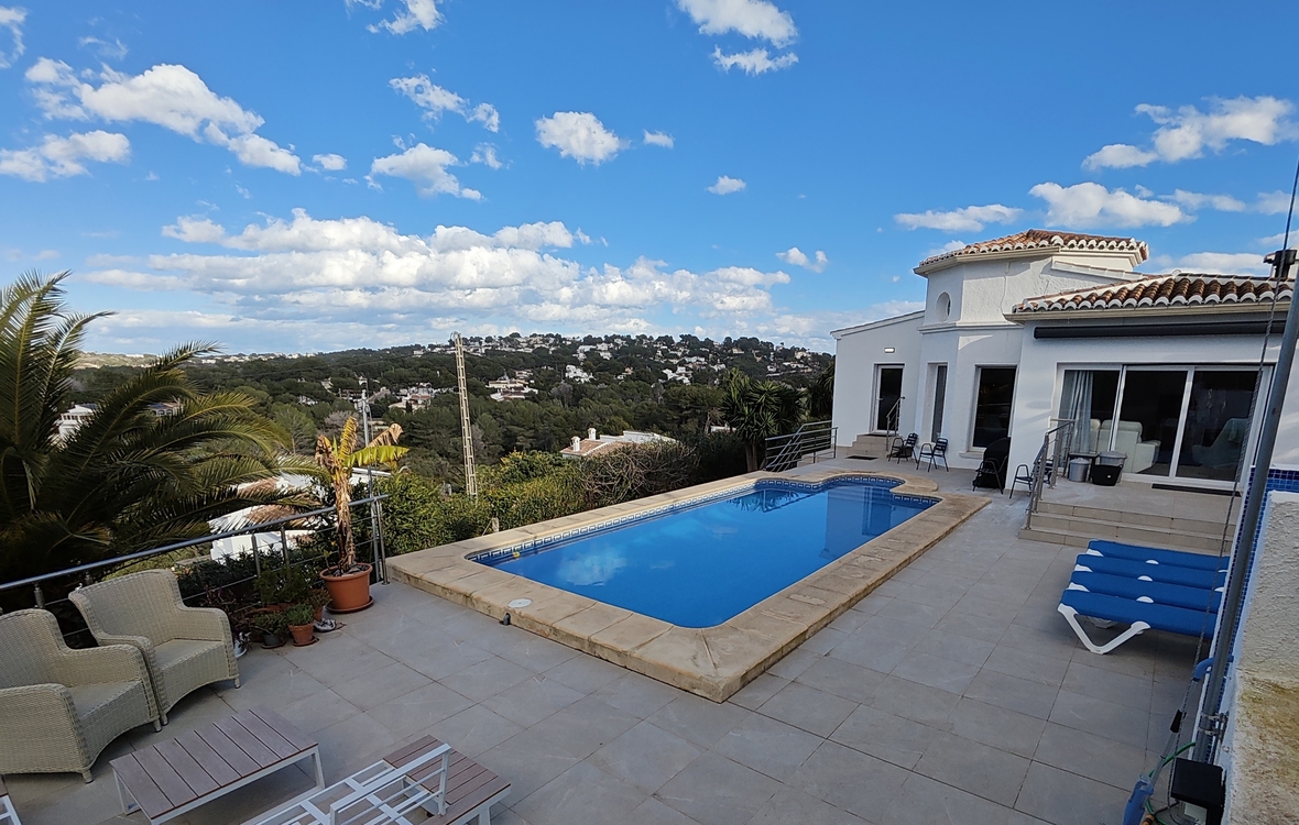 Terrasse extérieure avec piscine rectangulaire, bordure en pierre et solarium offrant une vue panoramique sur la vallée et les collines environnantes.