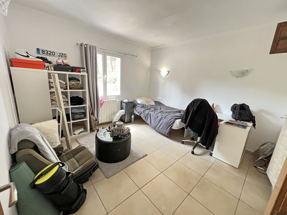 Chambre fonctionnelle avec sol en grès cérame, fenêtre en PVC blanc et radiateur. L'espace bénéficie d'un éclairage naturel et d'appliques murales.