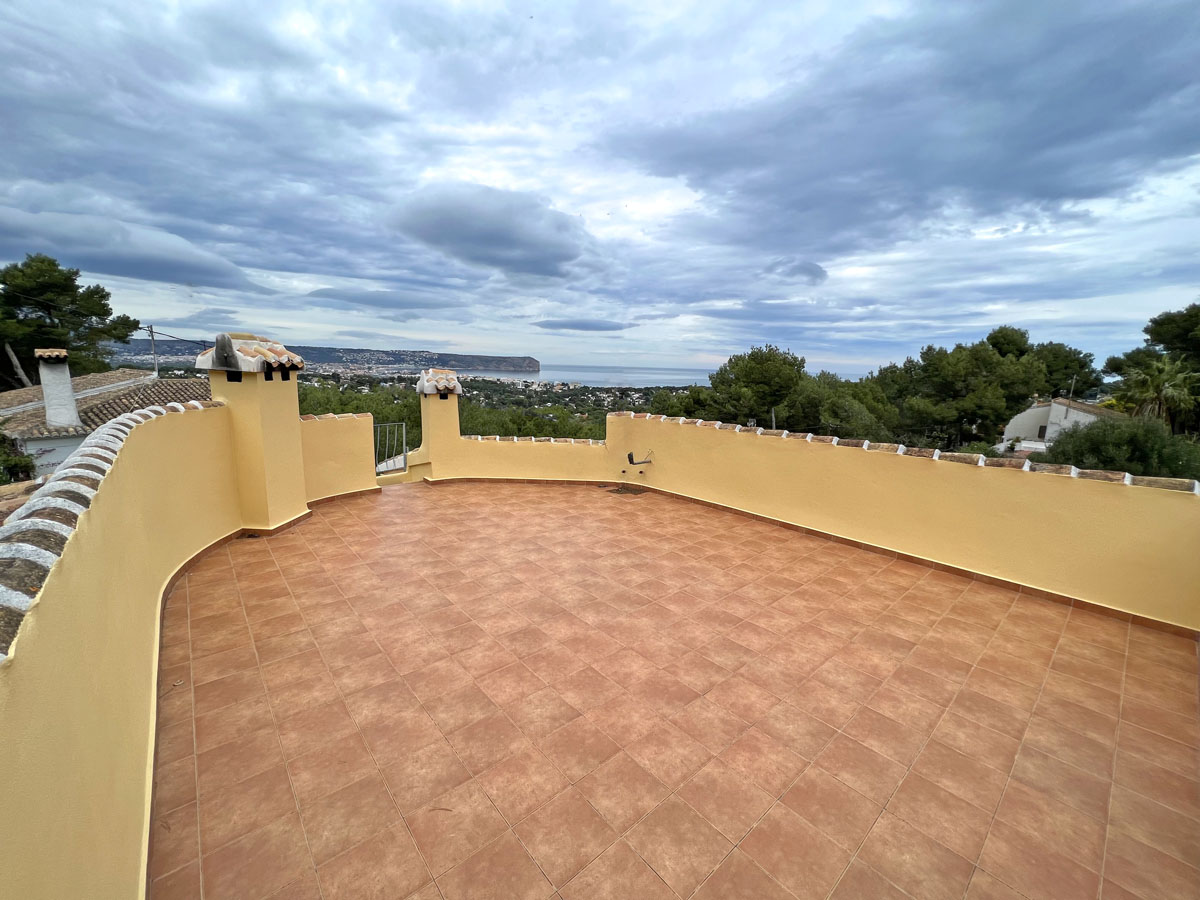 Grande terrasse solarium avec carrelage en terre cuite et muret incurvé, offrant une vue panoramique sur la mer Méditerranée et le Cap San Antonio.