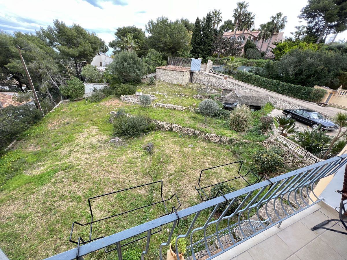 Vue surélevée depuis la terrasse sur le terrain en restanques avec murs en pierre sèche et végétation méditerranéenne environnante.