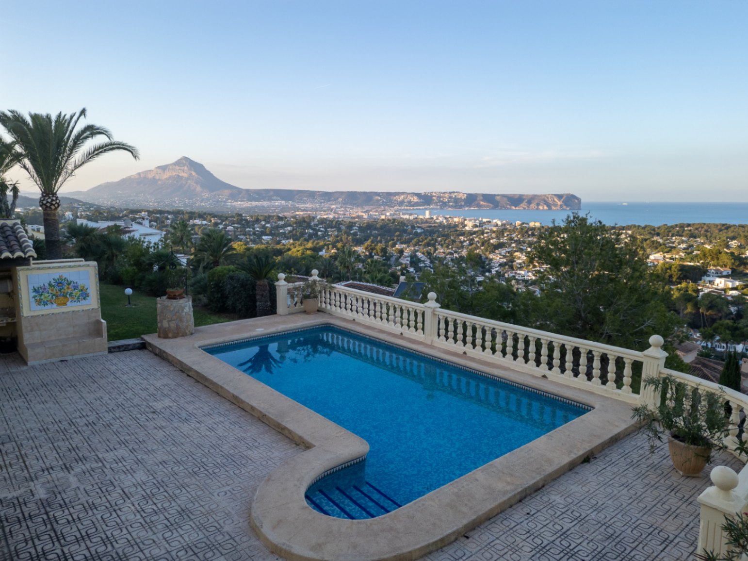 Piscine avec escalier romain et balustrade en pierre, offrant une vue panoramique sur la baie de Jávea, la mer Méditerranée et le Montgó.