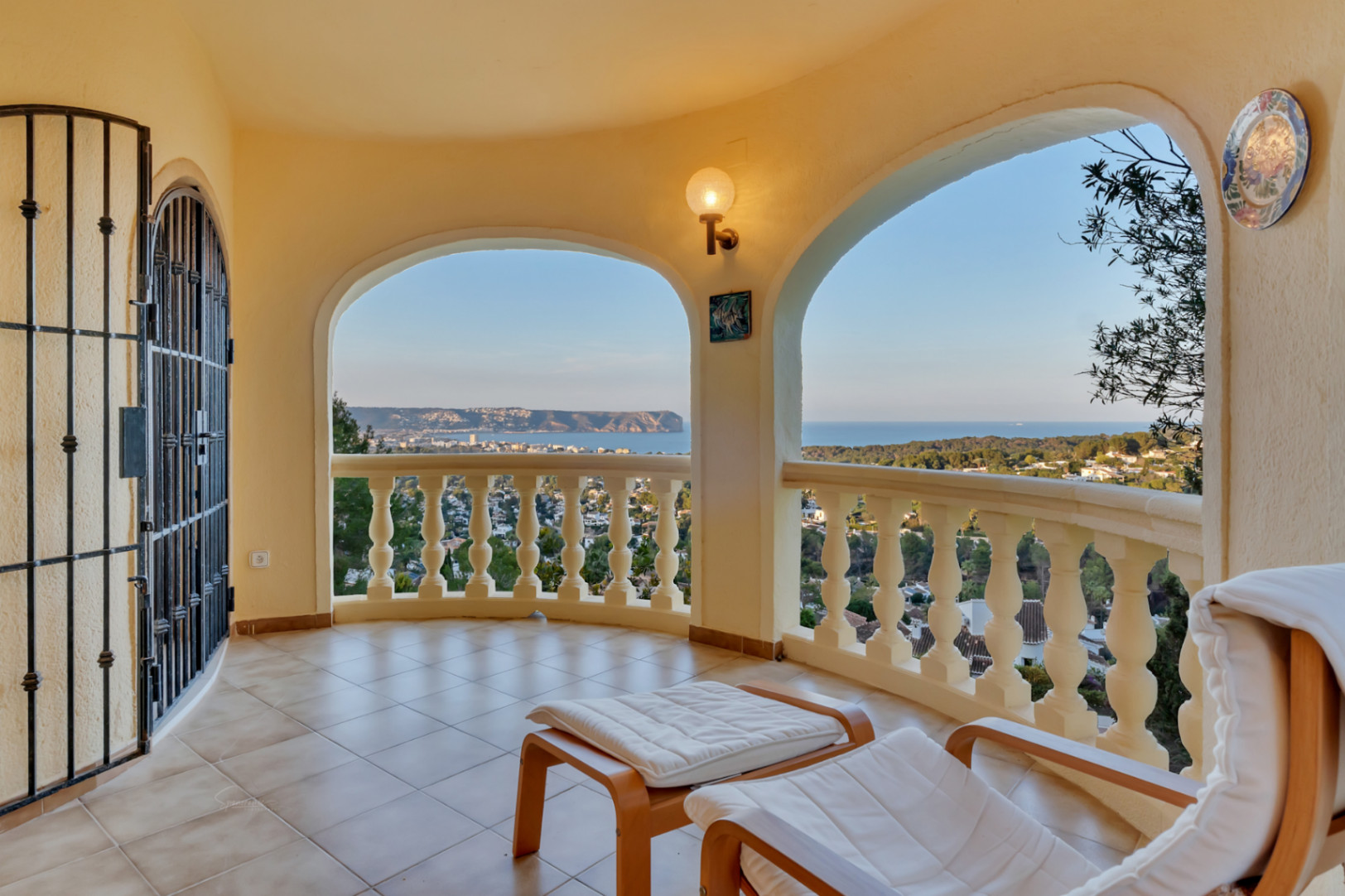 Terrasse couverte avec arches et balustrade classique, offrant une vue panoramique sur la baie de Jávea et le Cabo San Antonio depuis un sol en grès.
