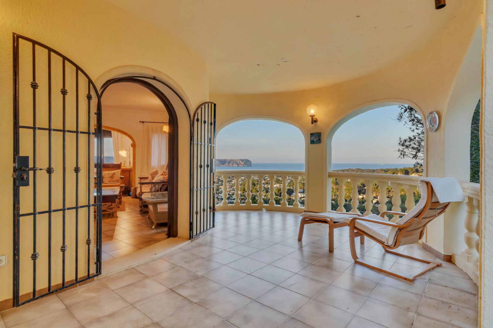 Terrasse couverte avec arches et balustrade classique offrant une vue sur le Cabo San Antonio. Sol en grès et accès au salon par une porte en fer forgé.