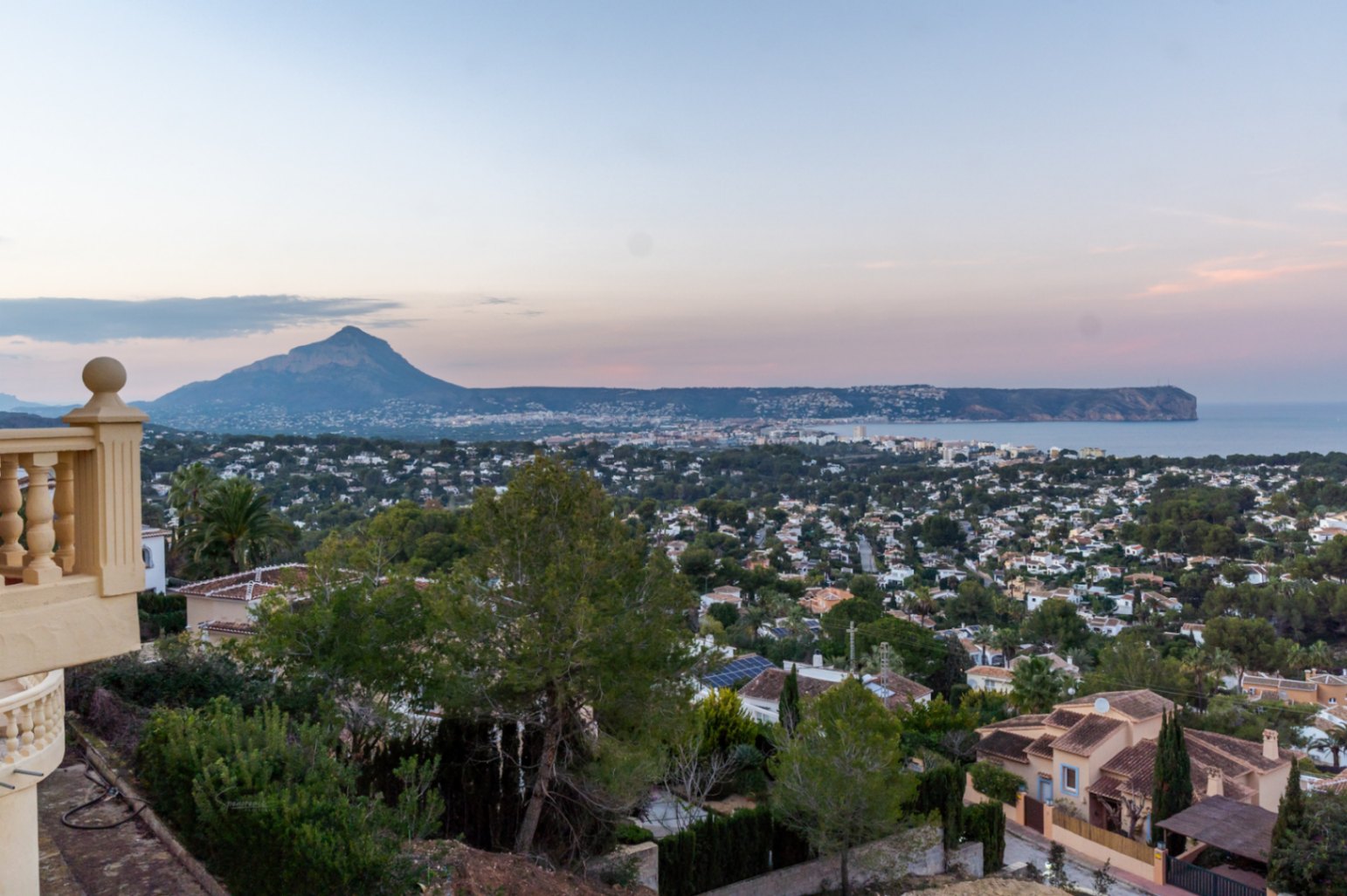 Vues panoramiques depuis la terrasse sur la baie de Jávea, le mont Montgó et le Cabo San Antonio au crépuscule, surplombant un paysage méditerranéen.