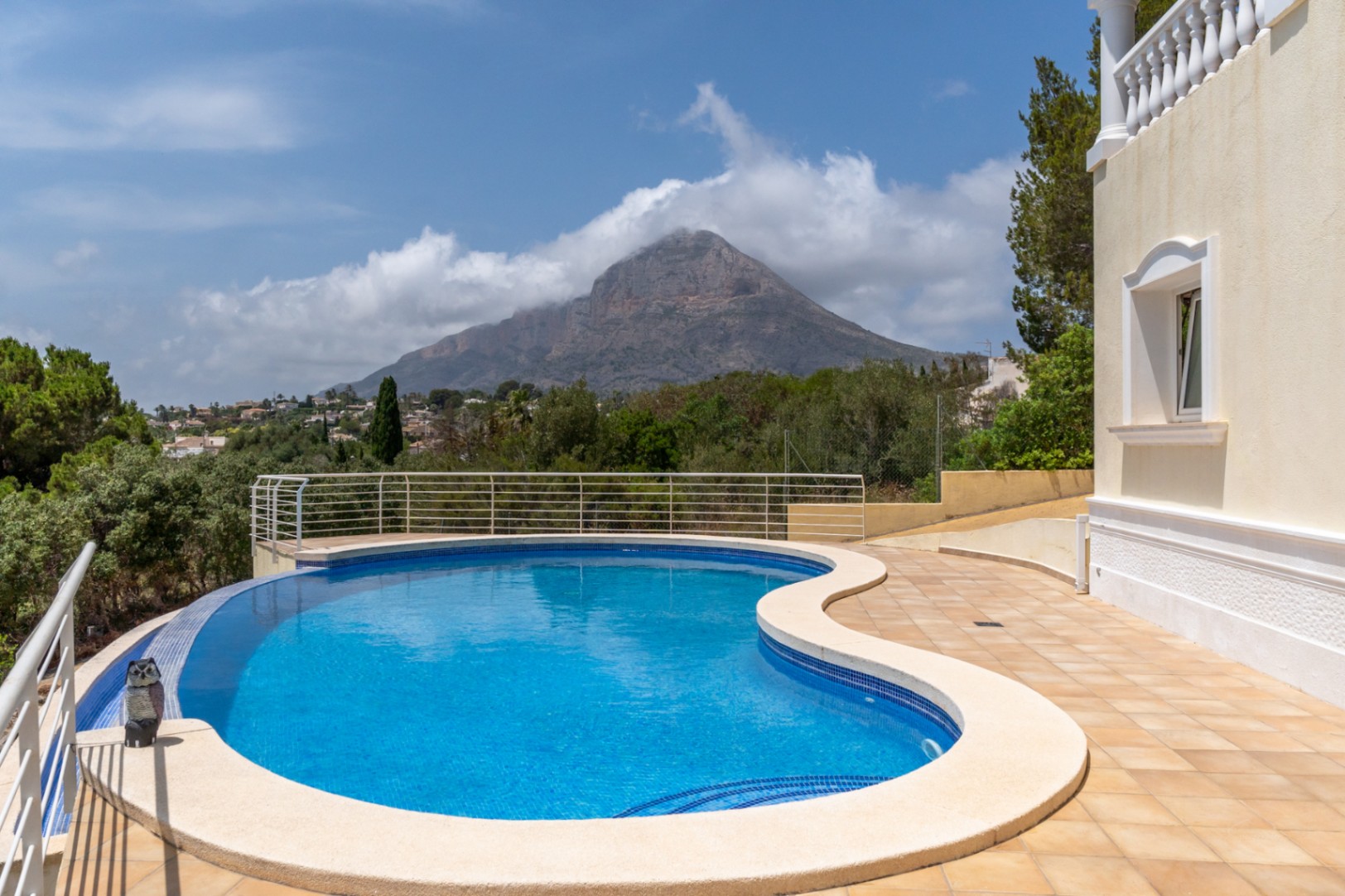 Piscine à débordement aux formes courbes avec vue imprenable sur le Montgó, entourée d'une terrasse carrelée et d'un garde-corps discret.