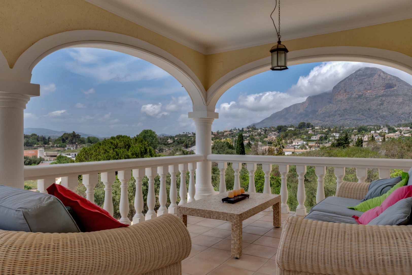 Terrasse couverte avec arches classiques, mobilier en osier et vue panoramique imprenable sur la vallée et le mont Montgó.