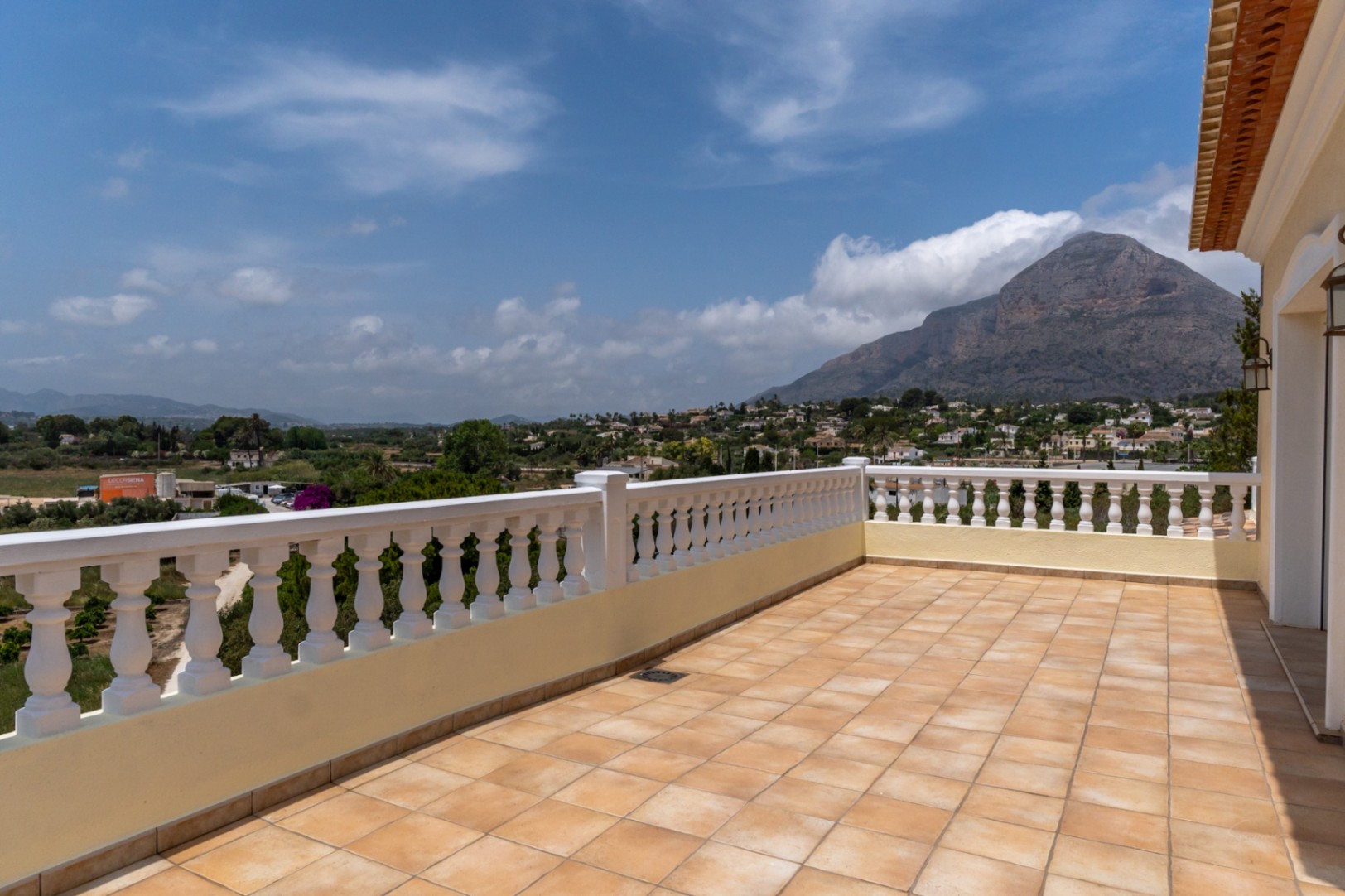 Terrasse supérieure avec carrelage en terre cuite et balustrade blanche, offrant une vue panoramique sur le mont Montgó et la vallée environnante.