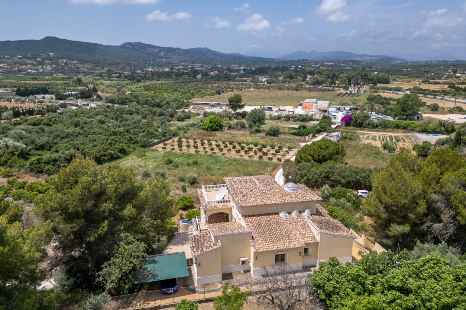 Vue aérienne de la villa montrant son toit en tuiles, sa coupole centrale vitrée et ses lucarnes circulaires, entourée par la vallée et les montagnes.