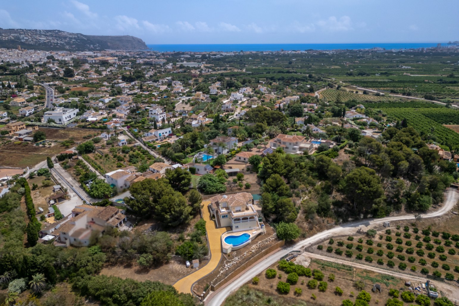 Vue aérienne de la villa soulignant sa position dominante, avec piscine à débordement et allée privée, offrant un panorama sur la vallée de Jávea et la mer Méditerranée.