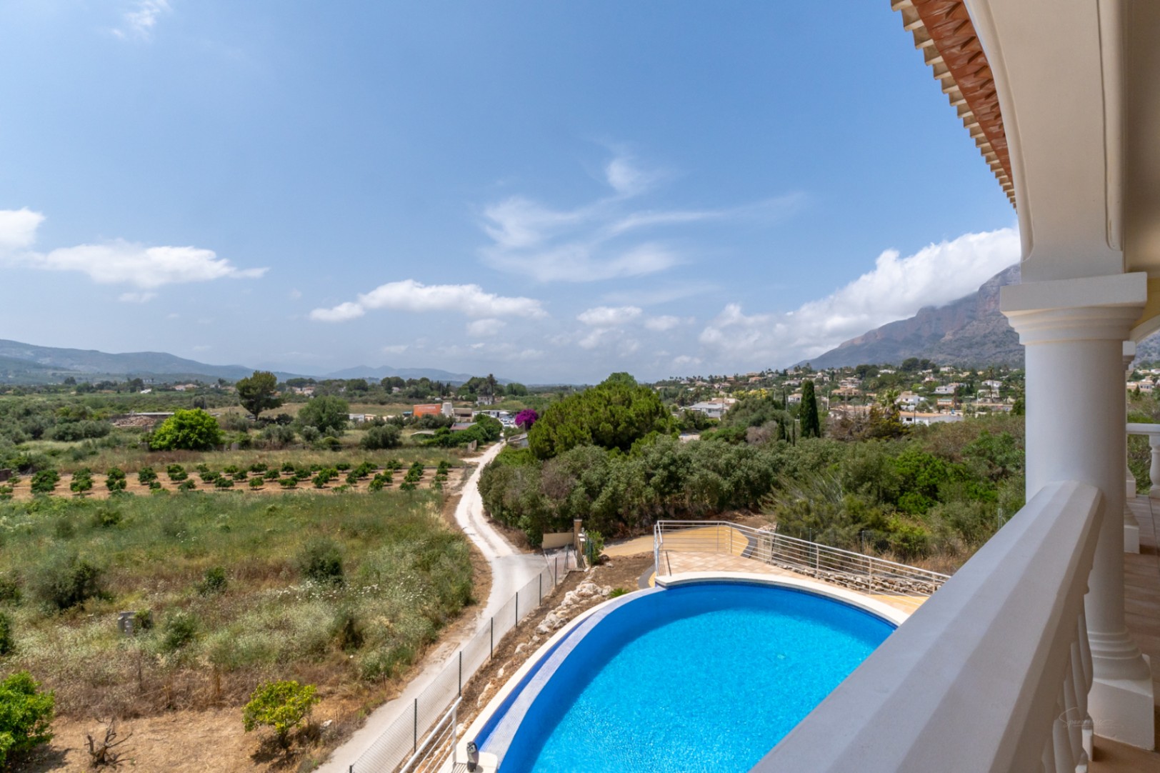 Vue surélevée depuis la terrasse dévoilant la piscine ovale et un panorama à 180º sur la vallée environnante et le mont Montgó.