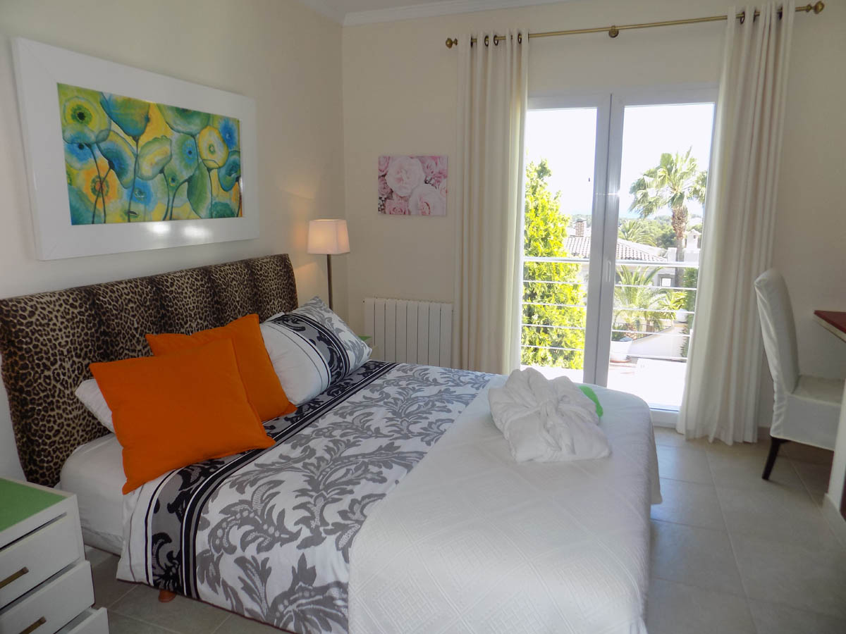 Chambre avec tête de lit léopard, literie à motifs et accès direct à une terrasse ensoleillée offrant une vue dégagée sur le jardin méditerranéen.