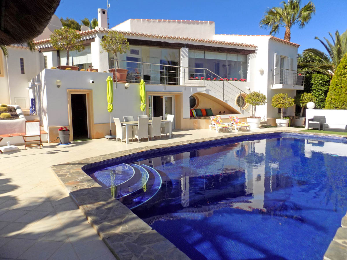 Vue extérieure avec piscine de 12m x 5,5m, terrasse ensoleillée, coin repas et espace détente intégré sous l'escalier menant à l'étage principal.