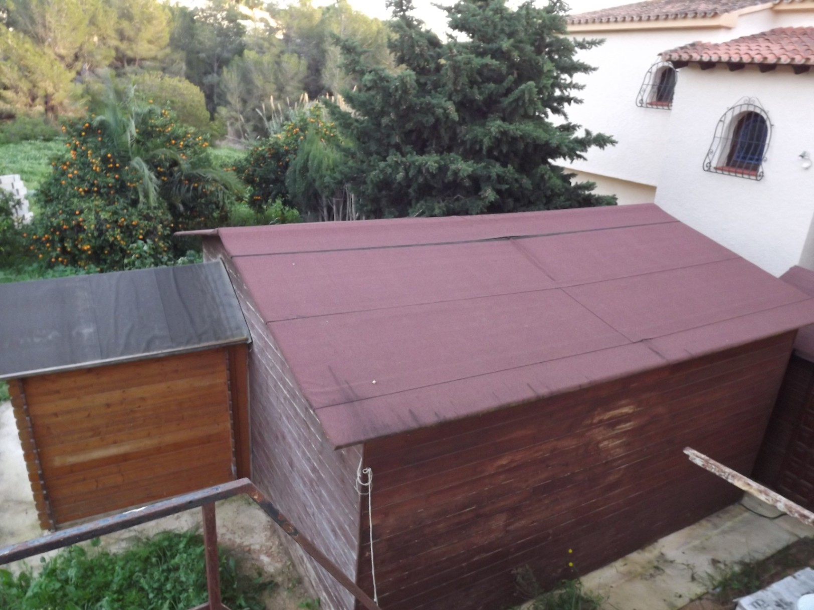 Abri de jardin en bois pour le rangement, situé sur le grand terrain arboré avec vue sur les orangers et l'architecture méditerranéenne de la villa.