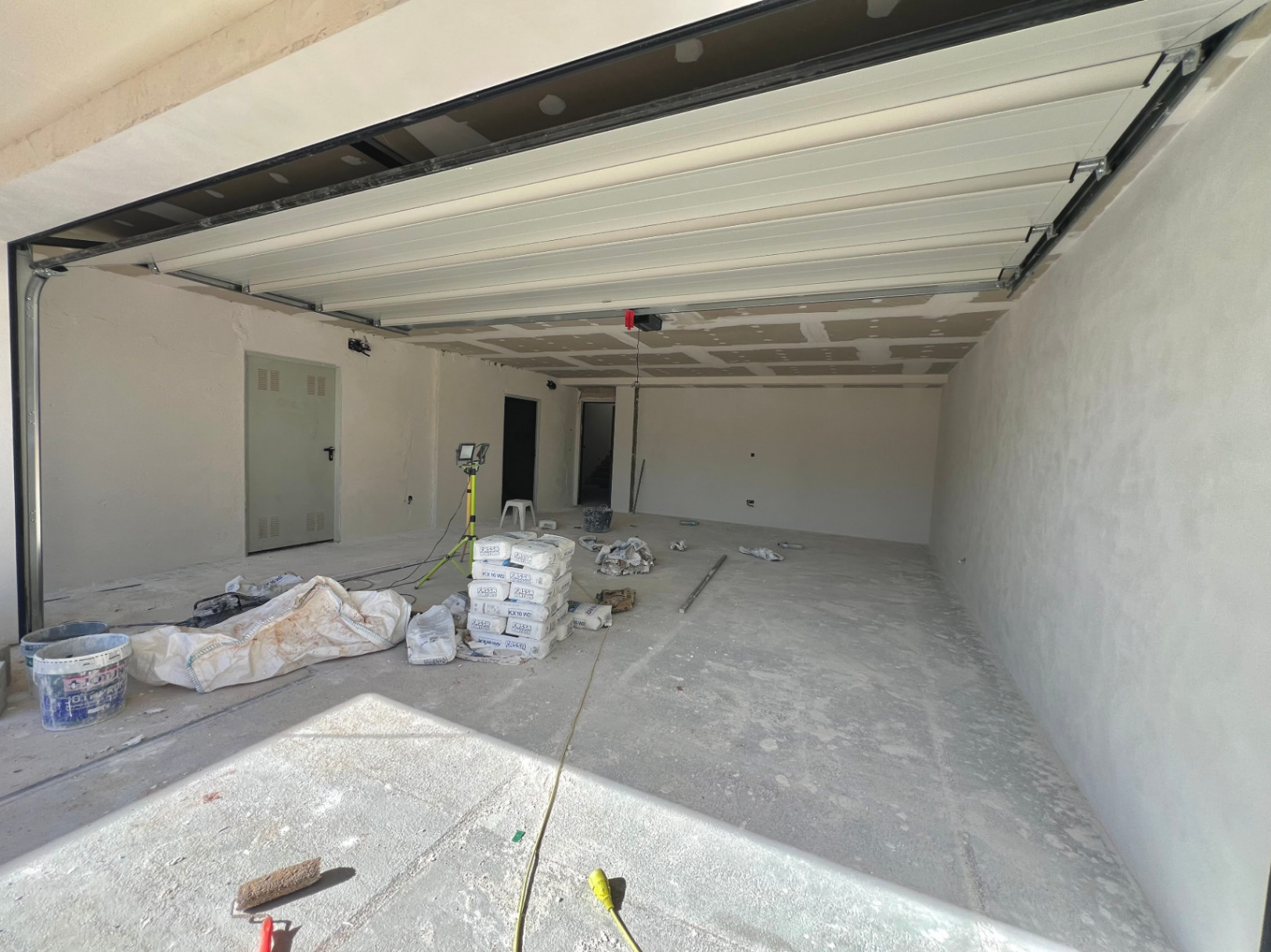 Grand garage en cours de construction avec porte sectionnelle automatique, sol en béton et accès direct à l'intérieur de la villa à Jávea.